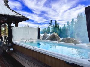 a jacuzzi tub on a deck with a view at Sugarloaf Summit Rare Tamarack Ski Inout Estate in Donnelly