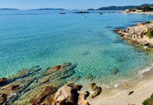 a beach with clear blue water and rocks at Saint clair in Le Lavandou