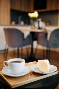 un trozo de pastel y una taza de café en una bandeja en Apartament Zakopiański z ogródkiem - Jacuzzi & Sauna & Siłownia & Plac Zabaw, en Zakopane