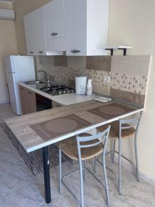 una cucina con tavolo con due sedie e lavandino di Casa Giulia a Saline Joniche