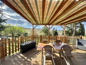 patio ze stołem i krzesłami na drewnianym tarasie w obiekcie GITE DE L'AUXINEILL w mieście Castelnou