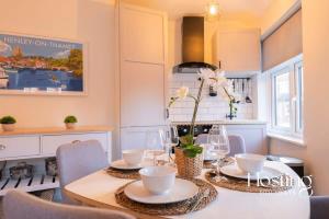 a dining room with a table with plates and glasses at Stylish 2 Bedroom Apartment Close To The River & Station in Henley on Thames