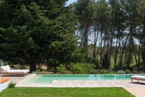 a swimming pool in a yard with benches and trees at Dimora Dei Semplici in Cisternino