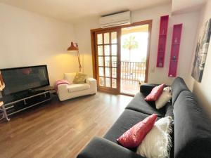 a living room with a couch and a television at Ensuite Double Room with Sea View in a Shared Apartment in the Centre of Santa Eularia - close to the Beach in Santa Eularia des Riu