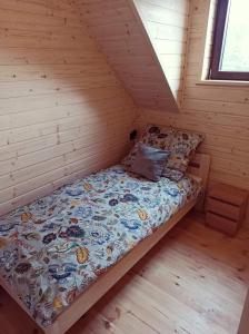 a bed in a cabin with a wooden floor at Domek pod Dębami Bogaczewo in Bogaczewo