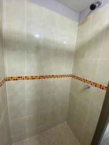 y baño con ducha y azulejos blancos. en Casa Mango, en Cali