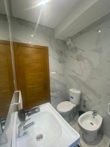 a white bathroom with a toilet and a sink at Appartement Chic et Luxueux Corniche Tanger in Tangier