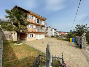 a fence in front of a house with a palm tree at Apartman Ana in Rijeka