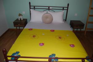 a bed with a yellow blanket with flowers on it at Casa Edelsy Bienvenid@s a un oasis de tranquilidad Descubre el encanto de Creta desde nuestra casa de ensueño! Tranquilidad, comodidad y elegancia. Explora Creta desde nuestro acogedor hogar Una escapada inolvidable te espera. in Neápolis
