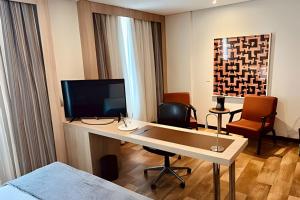 een kamer met een bureau, een televisie en een bed bij Apto Executivo no Intercity in Manaus