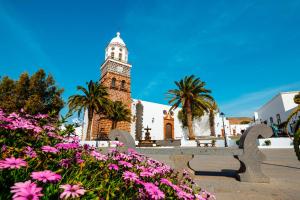 a building with a clock tower with pink flowers at Casa Siempreviva in Teguise