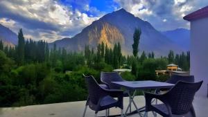 a table and chairs on a balcony with a mountain mural at IBEX Homestay Skardu in Skardu