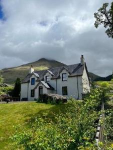 a white house with a hill in the background at Ferienhaus für 6 Personen ca 100 qm in Crianlarich, Schottland Loch Lomond and the Trossachs Nationalpark in Crianlarich