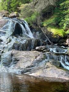 a river with a waterfall and rocks in the water at Ferienhaus für 6 Personen ca 100 qm in Crianlarich, Schottland Loch Lomond and the Trossachs Nationalpark in Crianlarich