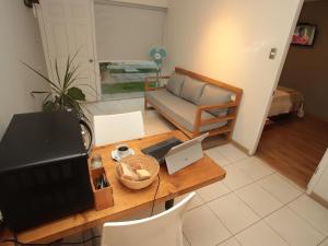 Zimmer mit einem Schreibtisch, einem Laptop und einem Sofa in der Unterkunft De Triana Hotel in Rancagua