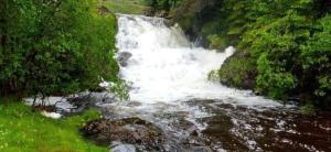 a waterfall in the middle of a river at Ferienhaus für 6 Personen ca 100 qm in Crianlarich, Schottland Loch Lomond and the Trossachs Nationalpark in Crianlarich