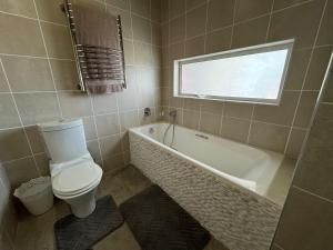 a bathroom with a toilet and a tub and a window at Cozy family beachfront house. in Langstrand