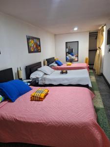 Habitación con 3 camas y mantas rojas y blancas. en HOTEL GALICIA PLAZA, en Manizales