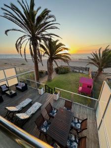 a deck with chairs and palm trees on the beach at Cozy family beachfront house. in Langstrand