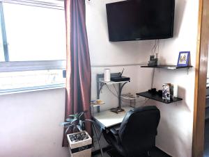 a room with a chair and a television on a wall at Departamentos Amueblados la Condesa in Mexico City