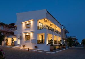 un edificio blanco con luces encendidas por la noche en Alexandrion Appartements Down Town, en Sarti