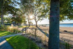 a walkway next to a beach with trees and a fence at Exclusive Cube mit Meerblick direkt am Strand Strandhaus in Hulshorst