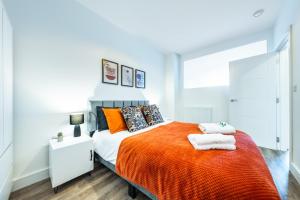 a bedroom with a bed with orange sheets and pillows at Modern 2 bed in Potters Bar - with FREE Parking- 4 min walk from the TRAIN STATION - DIRECT TRAINS TO LONDON in Potters Bar