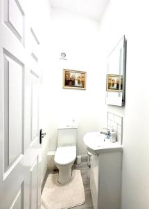 Baño blanco con aseo y lavamanos en Sutton Coach House, en Wexford