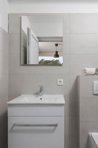La salle de bains blanche est pourvue d'un lavabo et d'un miroir. dans l'établissement Villa Piccola, à Labin