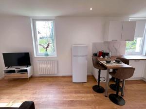 a kitchen with a white refrigerator and a table with chairs at Flat 2beds Bellegarde in Bellegarde-sur-Valserine