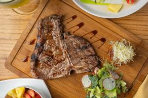a piece of steak on a cutting board with salad at Hotel Rivel - Restaurant & Nature Retreat in Turrialba