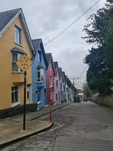 una calle con casas coloridas y un letrero de calle amarillo en Cobh Rambler en Cobh
