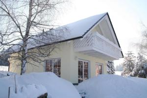 una casa ricoperta di neve con un mucchio di neve di Ferienhaus Vogtlandresidenz a Beerheide