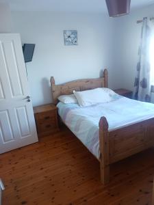 1 dormitorio con cama de madera con sábanas blancas en Cobh Rambler, en Cobh
