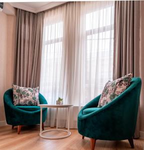 2 sillas y una mesa frente a una ventana en Hotel Well Inn, en Tiflis