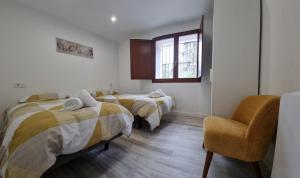 2 Betten in einem Zimmer mit einem Stuhl und einem Fenster in der Unterkunft Cathedral and Castle in Burgos + 22 Fotos