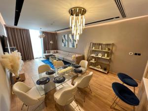 a dining room with a glass table and white chairs at Enjoy Luxury Condo with Sea View in Abu Dhabi