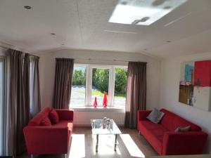 巴勒納紹的住宿－Mobilheim für 4 Personen ca 35 qm in Baarle-Nassau, Nordbrabant - b58367，客厅设有2张红色的沙发和1扇窗户