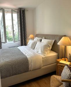 Un dormitorio con una cama con sábanas blancas y una ventana. en l'Alceste, en La Ciotat