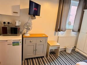 a small kitchen with a microwave and a tv on the wall at High Trees Guest House Gatwick in Hookwood