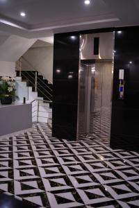 a lobby with black and white floors and stairs at Faletti’s Grand MM Alam Road in Lahore