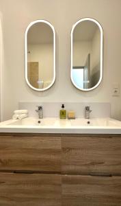 2 espejos sobre un lavabo blanco en el baño en l'Alceste en La Ciotat