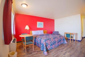 a bedroom with a bed and a table with chairs at Holiday Motel, Lordsburg By OYO in Lordsburg