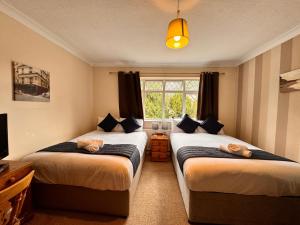 a bedroom with two beds and a window at High Trees Guest House Gatwick in Hookwood