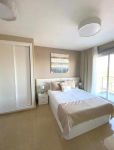 Un dormitorio con una cama grande y una ventana grande. en Apto Ciudad Jardin Vista mar Planta 5, en Oropesa del Mar 35 fotos más