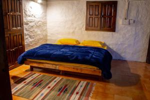 um quarto com uma cama com um cobertor azul e almofadas amarelas em Aarya homes em Manali
