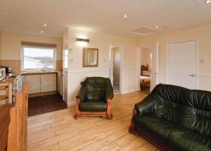 a living room with a leather couch and a kitchen at Anglesey Bungalows in Trearddur