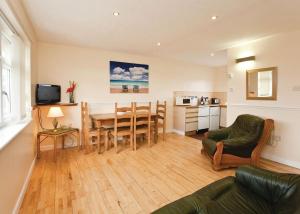 a living room with a table and chairs and a kitchen at Anglesey Bungalows in Trearddur