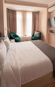 提比里斯的住宿－Hotel Well Inn，酒店客房设有一张白色大床和两把椅子