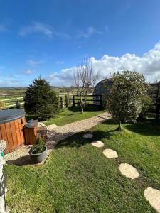 a garden with a fence and a tree in the grass at Cotswold shepherd hut with hot tub and sauna Dog friendly in Charlton
